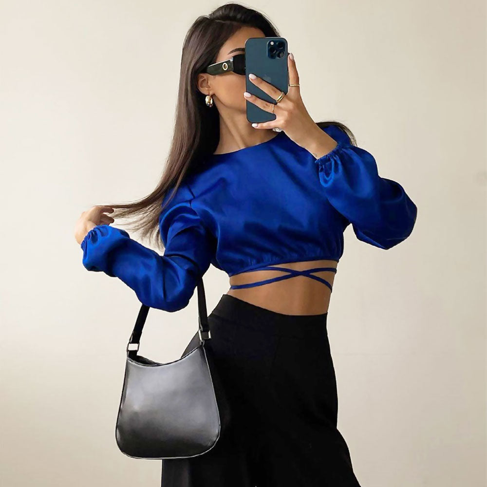 woman in blue crop top and black pants posing with purse
