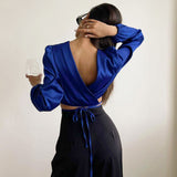 woman in blue crop top and black pants holding a glass
