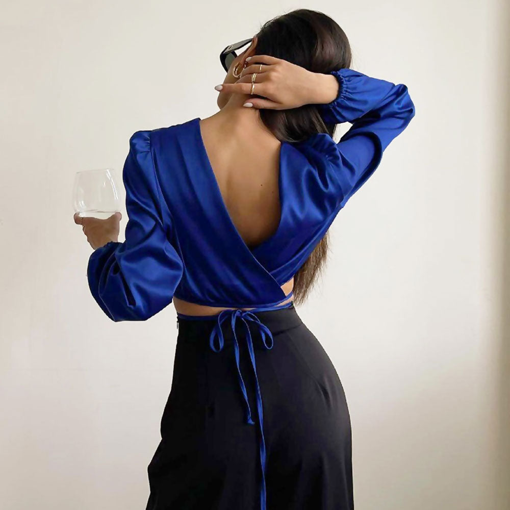 woman in blue crop top and black pants holding a glass