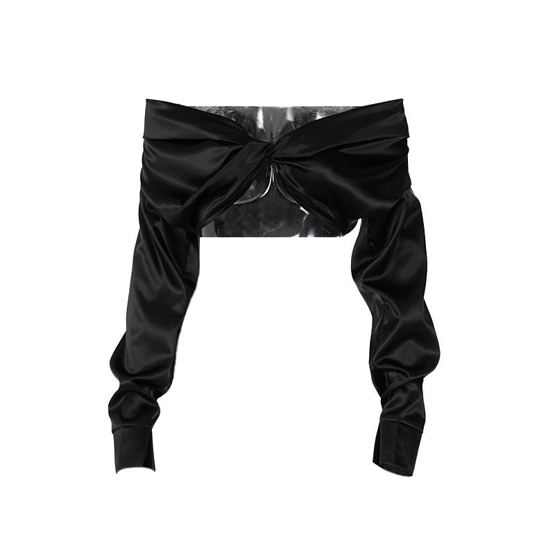 A black satin off-the-shoulder cropped top with a twisted front and long sleeves, shown flat.