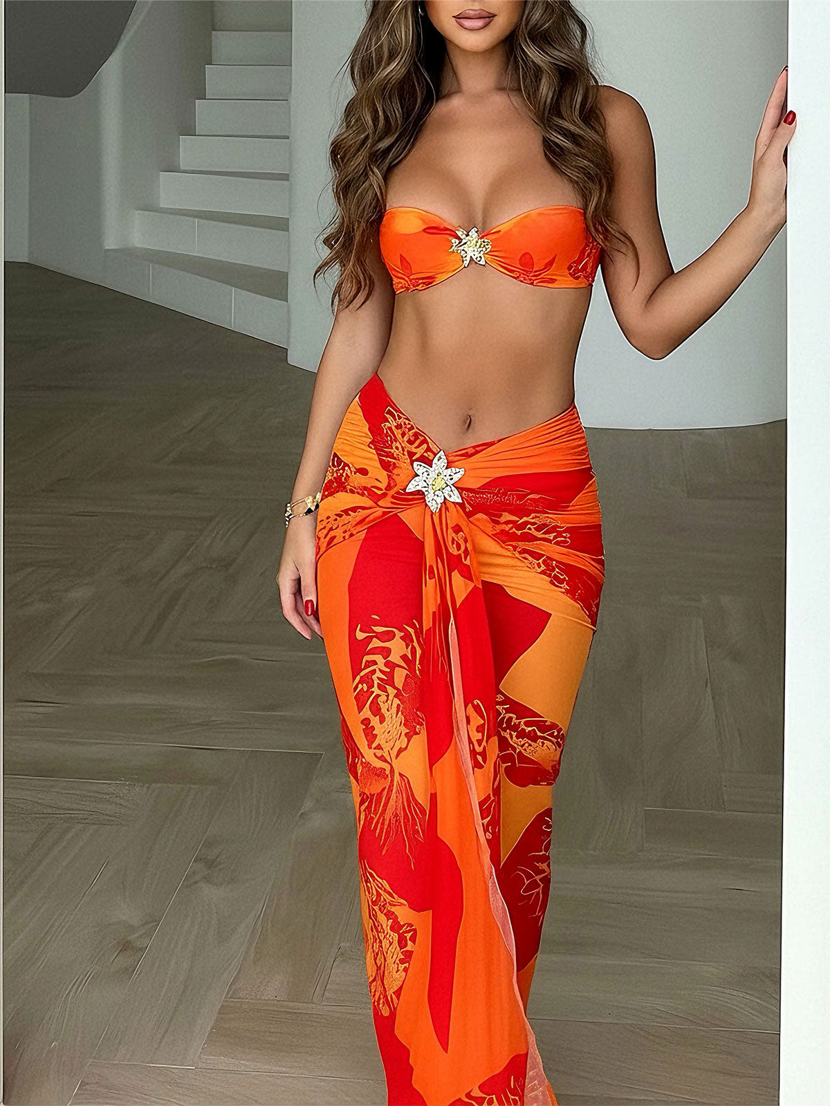 Woman wearing an orange and red floral print bikini with a matching sheer sarong skirt.
