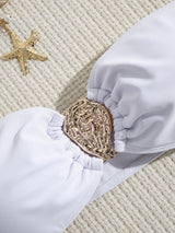 Close-up of the gold hardware embellishment on a white bikini top.