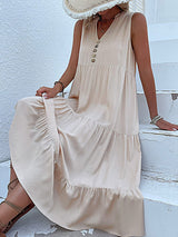 woman sitting on white steps wearing a beige tiered midi dress and gladiator sandals
