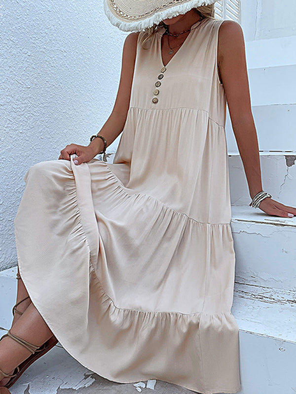 woman sitting on white steps wearing a beige tiered midi dress and gladiator sandals