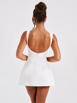 back view of woman in white sleeveless mini dress with low back