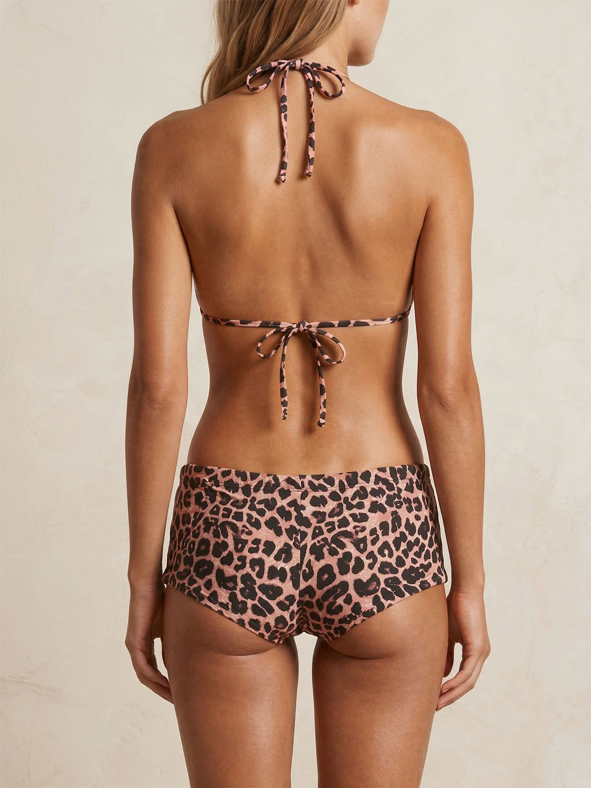 Woman wearing a leopard print bikini with halter top and shorts, back view
