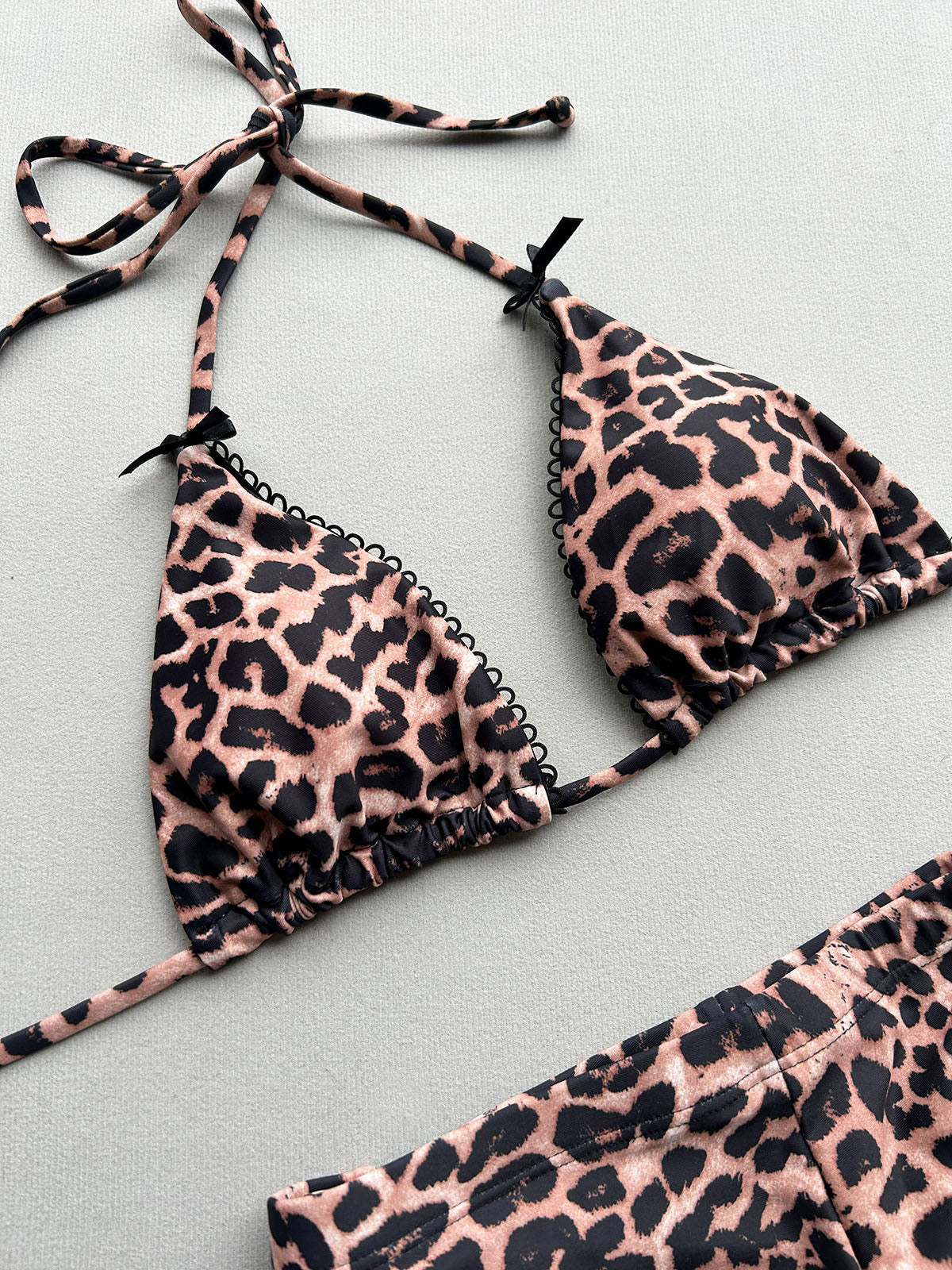 Close-up of a leopard print bikini top with bow accents and scalloped trim