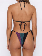 Back view of a woman in a sequined bikini with purple, teal, and black panels.