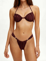 Woman wearing a brown ruched bikini with gold accents.