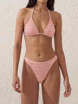 Woman wearing a pink textured triangle bikini with a halter neck and high-cut bottoms.