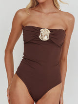 woman wearing a brown strapless swimsuit with a gold and pearl embellishment on the bust