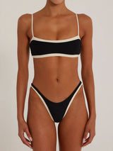 Front view of a woman wearing a black and cream bikini with a bandeau-style top and high-cut bottoms.