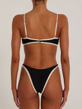 Back view of a woman wearing a black and cream bikini with adjustable straps and a clasp closure.