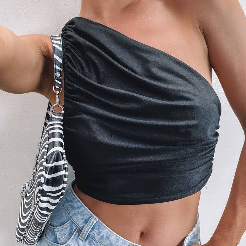 woman wearing a black one-shoulder ruched cropped top with blue jeans and a zebra print handbag