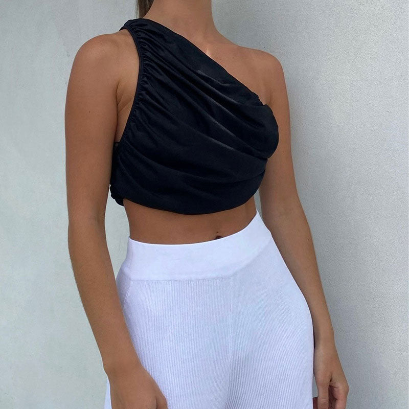 woman wearing a black one-shoulder ruched cropped top with white high-waisted pants