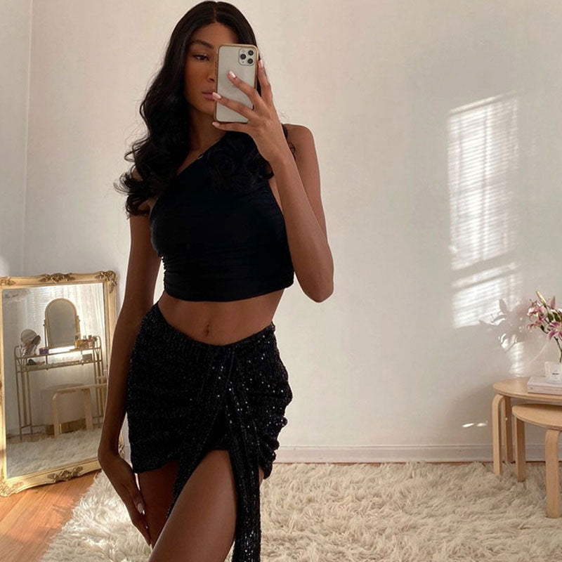 woman wearing a black one-shoulder ruched cropped top with a black sequined mini skirt