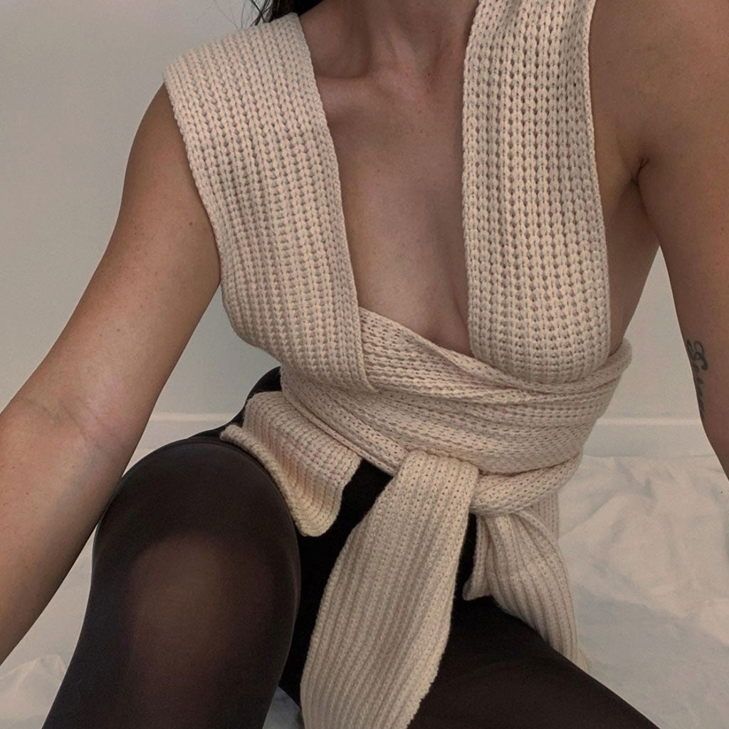 Close-up of a woman wearing a cream knit wrap top tied around her waist
