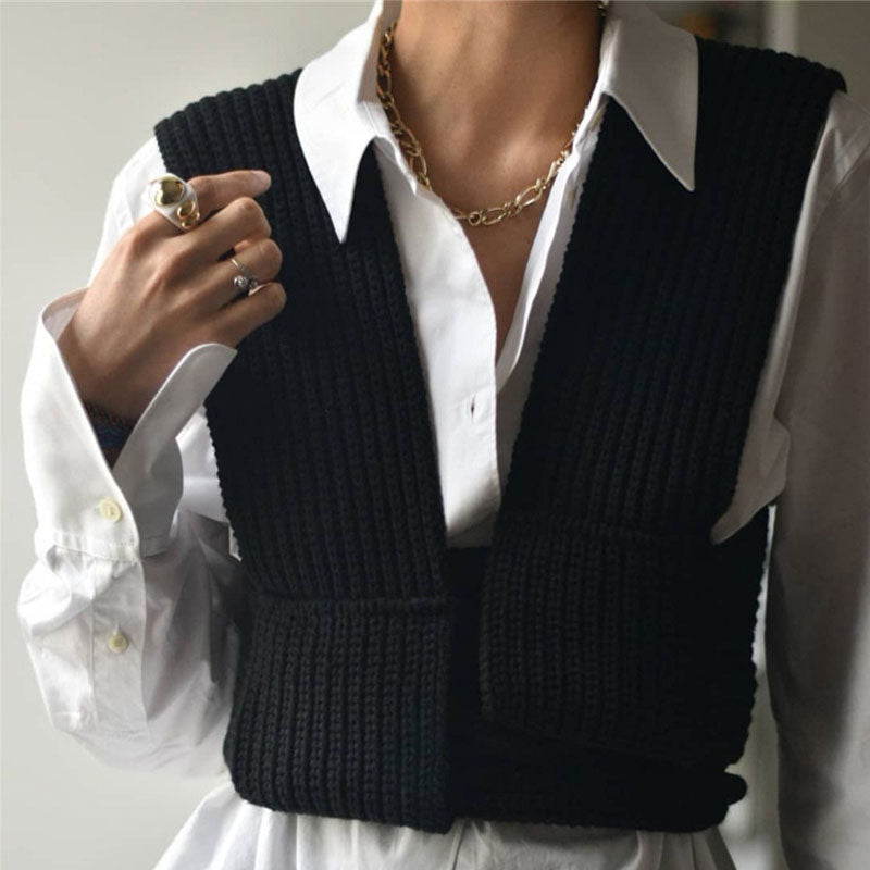 A woman wearing a white collared shirt with a black knitted vest.