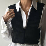 A woman wearing a white collared shirt with a black knitted vest.