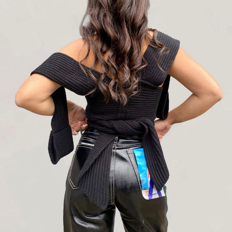 The back of a woman wearing a black knitted wrap top tied at the waist.