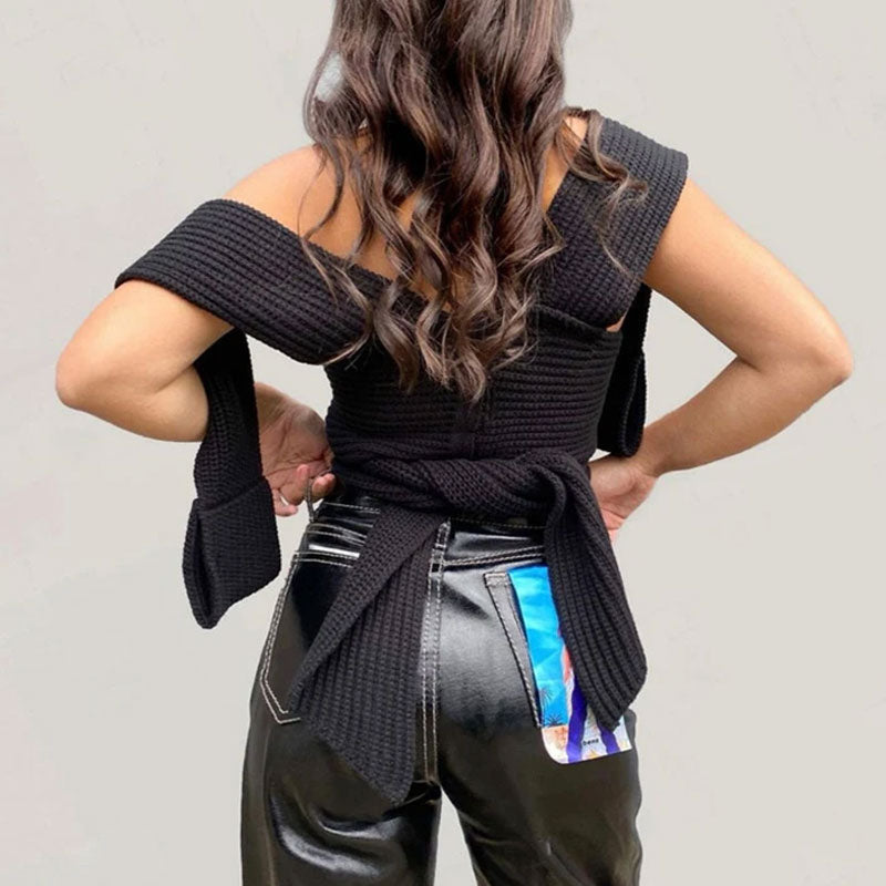 Back view of a woman wearing a black knitted wrap top and leather pants