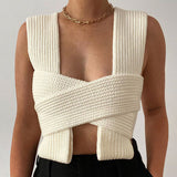 Close-up of a woman wearing a white knit wrap top with a gold chain necklace.