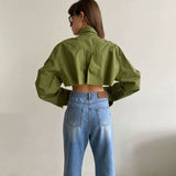 Woman wearing a green cropped button-down shirt with blue jeans, back view