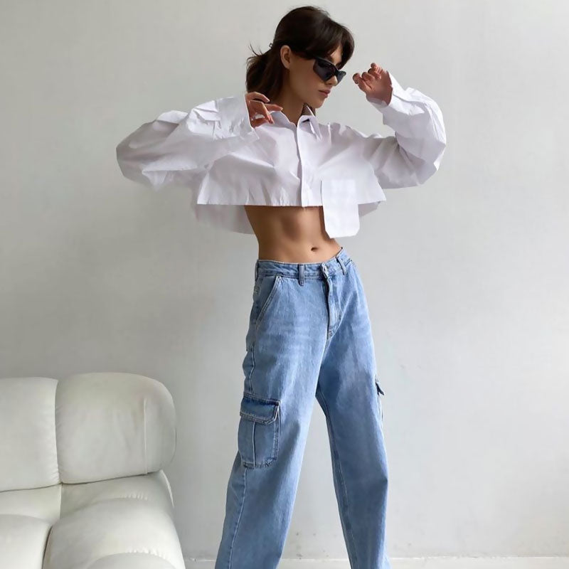 Woman in a white cropped shirt and light blue cargo pants posing with sunglasses