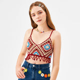 A young woman with long brown hair and colorful hair clips is wearing a crochet crop top and embellished jeans.