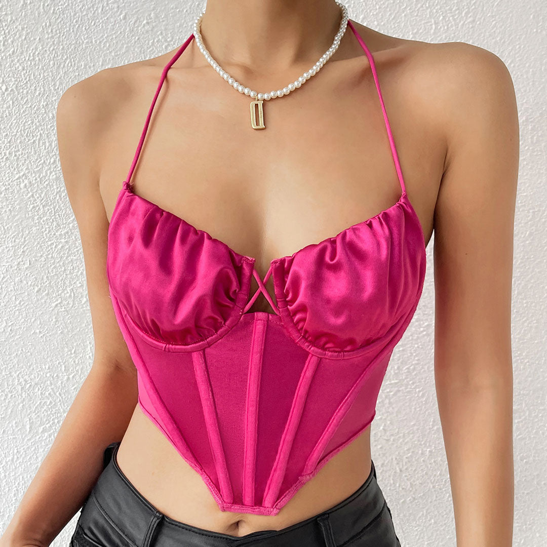 Close-up of a woman in a fuchsia halter neck corset top.