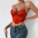 Side view of a woman wearing a red satin corset top and jeans.