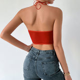 Back view of a woman wearing a red satin corset top and jeans, showing the low back design.