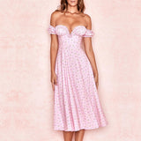 Woman wearing a pink floral off-the-shoulder midi dress with a sweetheart neckline and ruffled trim, standing against a pink background.