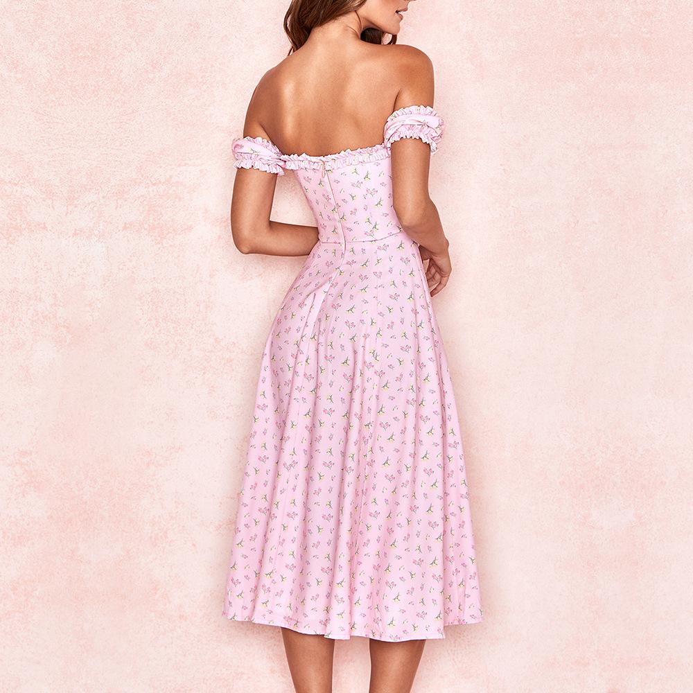 Back view of a woman wearing a pink floral off-the-shoulder midi dress with a sweetheart neckline and ruffled trim, standing against a pink background.