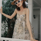 A woman in a floral dress and straw hat posing on a porch.