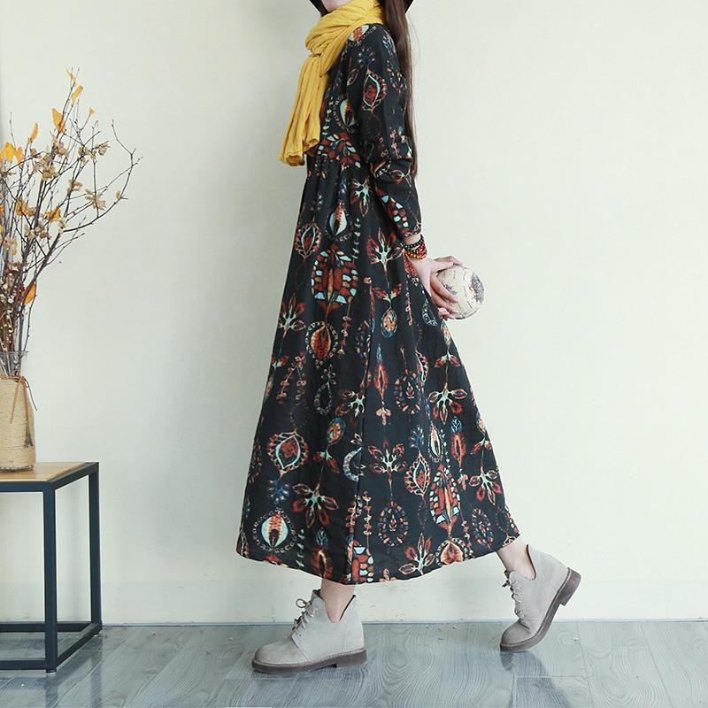 Woman wearing a black floral print midi dress with a yellow scarf and gray boots