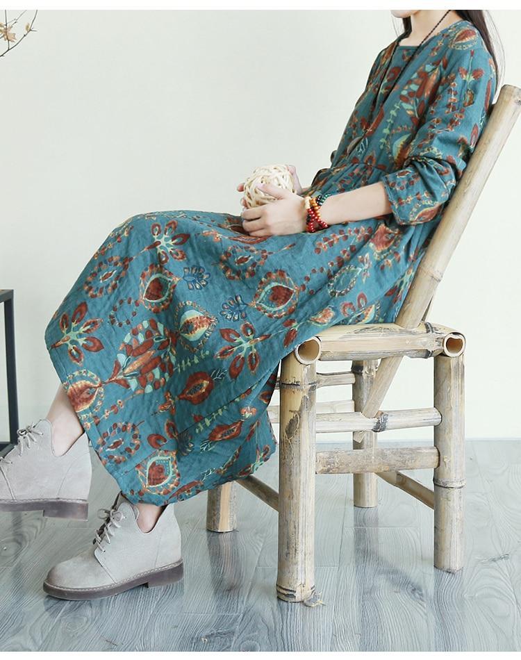 Woman sitting on a bamboo chair wearing a teal floral print midi dress