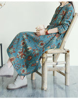Woman sitting on a bamboo chair wearing a teal floral print midi dress
