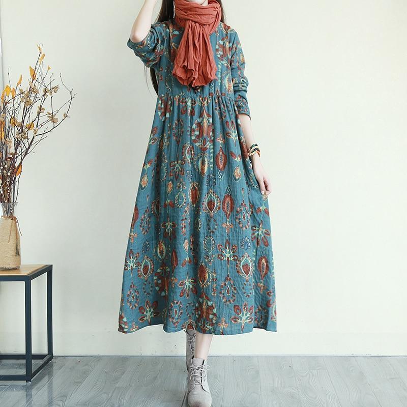 Woman wearing a teal floral print midi dress with an orange scarf and gray boots