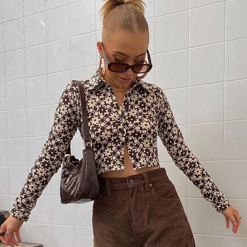Woman wearing a brown and white patterned long-sleeved cropped shirt and brown corduroy pants, with sunglasses and a brown shoulder bag.