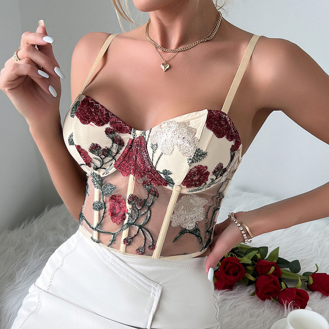 Close-up of a woman's chest wearing a cream corset top with floral embroidery