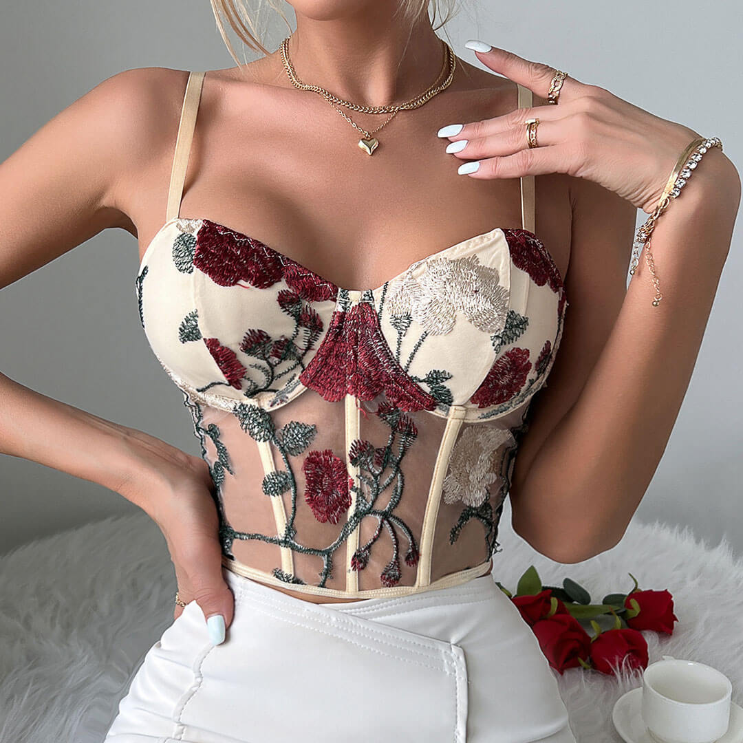 Woman posing with hands on hips wearing a cream corset top with floral embroidery
