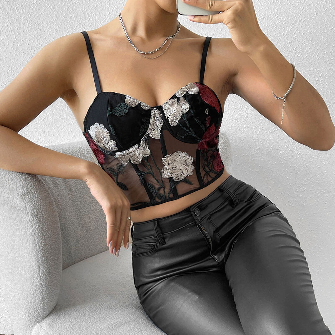 Woman wearing a black floral embroidered corset top and black leather pants.