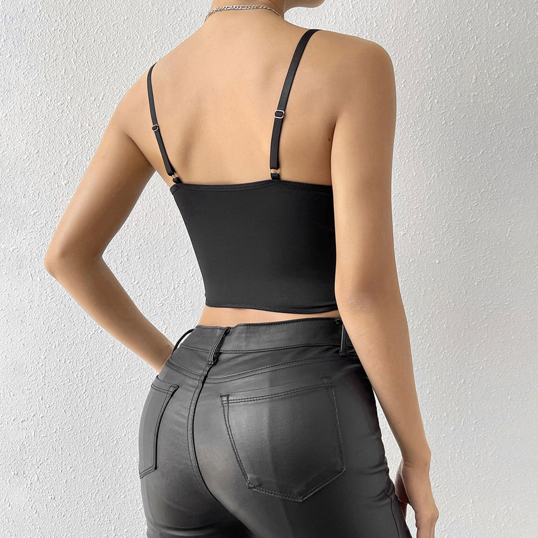 Back view of a woman wearing a black floral embroidered corset top and black leather pants.