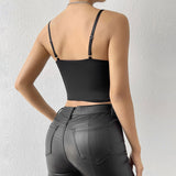Back view of a woman wearing a black floral embroidered corset top and black leather pants.