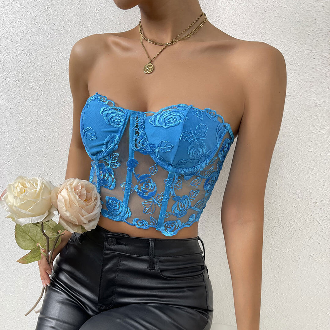 Close-up of a woman in a blue strapless lace corset top with intricate floral patterns.