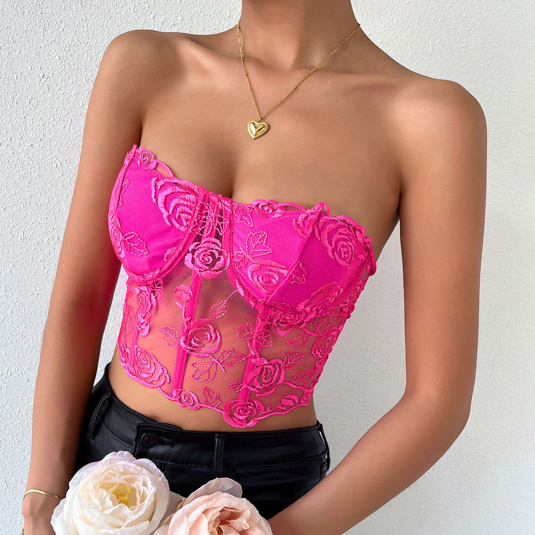 Close-up of the front of a pink lace corset top with floral details.