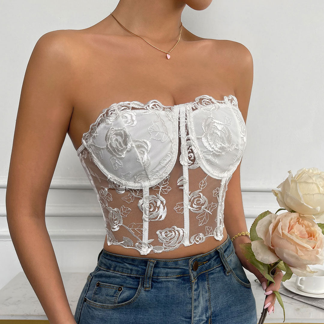 Close-up of a woman's torso wearing a white strapless lace corset top with floral details.