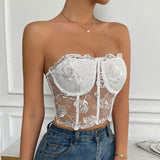 A woman in a white lace corset top and blue jeans holding a bouquet of roses.