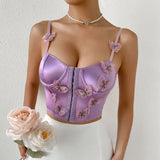 woman wearing a purple satin corset top with butterfly embellishments and a white skirt, holding pink roses